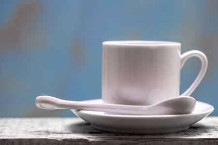 Porcelain coffee cup with spoon and saucer against a rustic background with copy spaceの写真素材