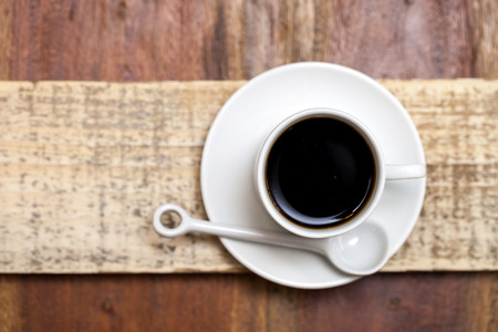 Top view of coffee cup with spoon and saucer on a rustic wooden tableの写真素材