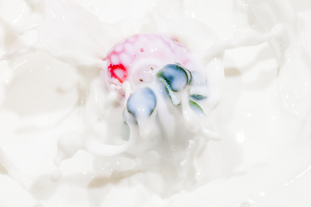 Strawberry falling in a bowl of milk with milk splashingの写真素材