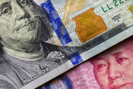 Close up of one hundred Dollar banknote over a 100 Yuan banknote with focus on portraits of Benjamin...