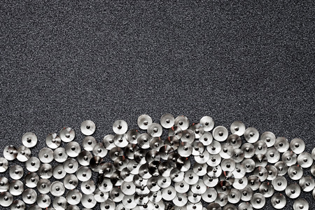 Abstract background with small round metallic objects on glittery silver background with copy space