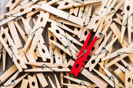 Single red clothespin on a pile of ordinary colored ones/abstract individuality, uniqueness conceptの写真素材