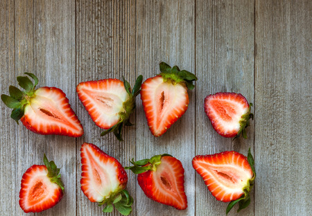 Fresh strawberries cut in half on wooden rustic background with copy spaceの写真素材