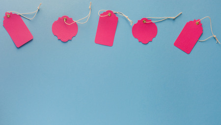Blank pink sale tag mock ups isolated on blue background with copy spaceの写真素材
