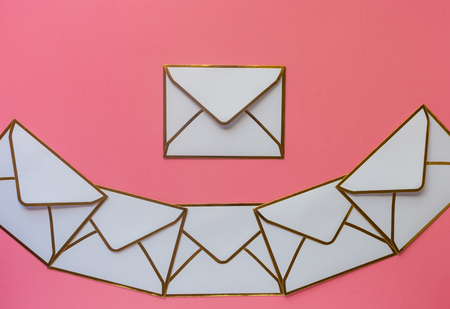 Stack of white envelopes with golden ridges on blush pink background with copy spaceの写真素材
