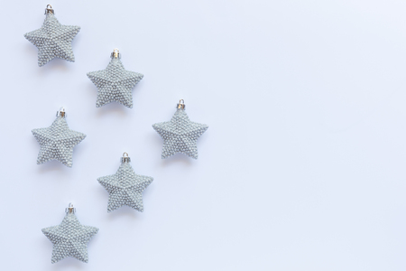 Pattern of silver glittery Christmas star ornaments on white background with copy spaceの写真素材