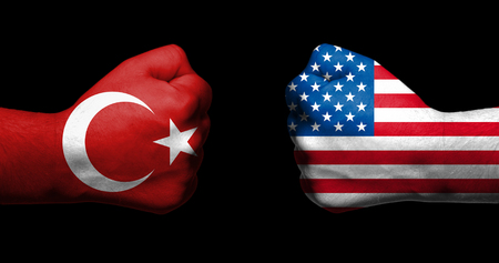Flags of Turkey and United States painted on two clenched fists facing each other on black background/Turkey - USA relations conceptの写真素材
