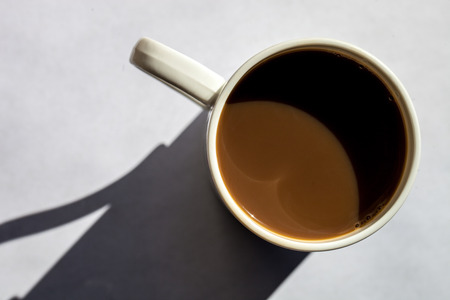 Minimalistic composition of top view coffee cup with hard shadows on white textured backgroundの写真素材
