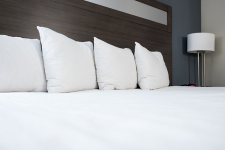 Bed with white sheets and pillows and bedside lampの写真素材
