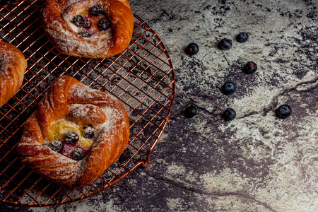Top view of golden chese danish pasties with blackberries and powder sugar