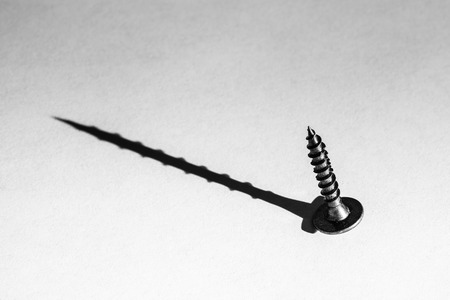 Damaged screw with perfect shadow - looks can be deceiving conceptの写真素材