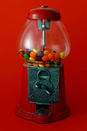 A gumball machine against on a red background.の写真素材