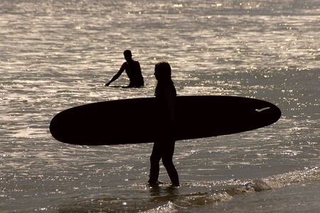 A silhouette of a female surfer during sunset.