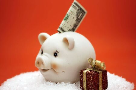 Money sticking out of a piggy bank with christmas gift. Could represent christmas savings.の写真素材
