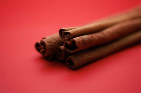 A bunch of cinnamon sticks on a red background.の写真素材