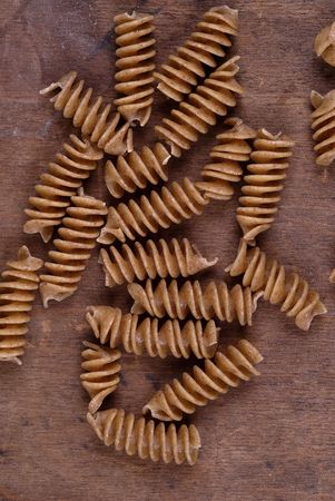 Wholewheat rotini pasta on an aged wooden table/cutting board.の写真素材