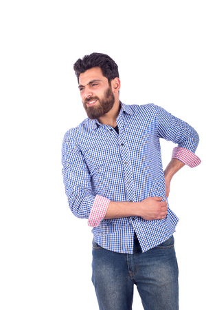Beard young man feeling pain and holding his waist,  guy wearing blue shirt and jeans, isolated on white backgroundの写真素材