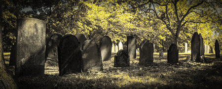 A panoramic view of a very old cemetery; photo done in seasonal halloween or fall colortones