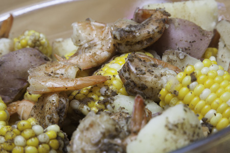 A glass bowl is filled with corn on the cob, red potatoes, and shrimp - a classic shrimp boil Everything is seasoned to perfection and steaming hot The photo has a shallow depth of field A glass bowl is filled with corn on the cob, red potatoes, and shrimp - a classic shrimp boil Everything is seasoned to perfection and steaming hot The photo has a shallow depth of field