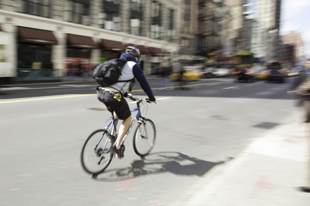 A cyclist rides his bicycle through the streets of New York City   Movement is shown by the blur caused by using a panning technique のeditorial素材