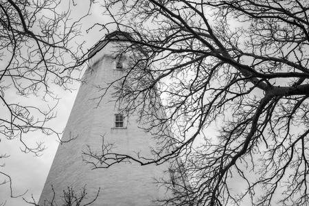 A view of the Sandy Hook lighthouse through the trees at Fort Hancock on Sandy Hook in New Jersey; This lighthouse is the oldest working lighthouse in the United Statesのeditorial素材