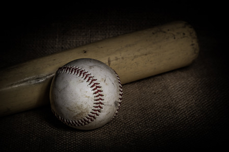 A worn baseball and bat sit on a burlap surface.  Image was lit by using a lightpainting technique.の写真素材