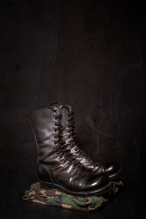 A pair of combat boots with camouflage fatique pants on a black background.の写真素材