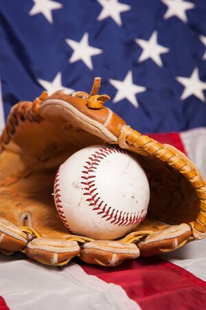 A baseball and glove with an American flag background.の写真素材