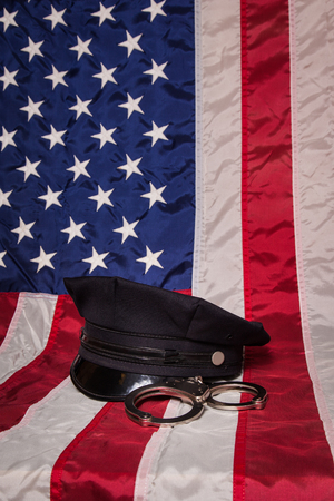A police hat with handcuffs on an American flag background.の写真素材