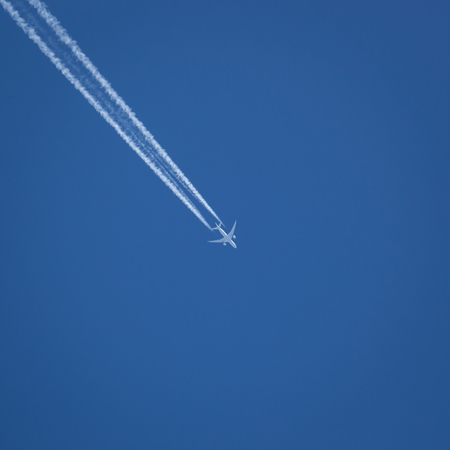 A commercial jet flies against a crisp blue sky.