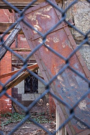 Details of architectural decay seen through a chain link fence.の写真素材