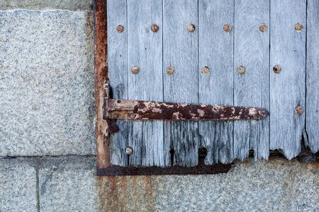 A closeup of an old wooden shutter with rusty metal accents.