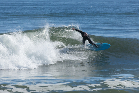 ASBURY PARK, NEW JERSEY - November 8, 2016: A surfer rides the waves on a beautiful fall day.のeditorial素材