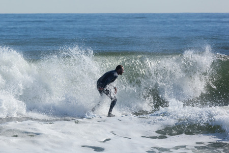 ASBURY PARK, NEW JERSEY - November 8, 2016: A surfer rides the waves on a beautiful fall day.のeditorial素材