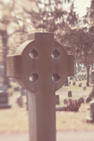 An old Celtic Cross is blurred in a cemeteryの写真素材