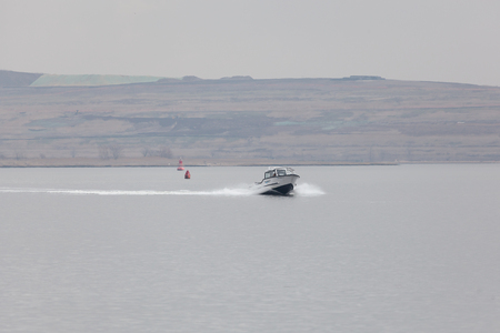 SEWAREN, NEW JERSEY - April 5, 2017: An Atlantic Response Inc. boat travels the Arthur Kill in Woodbridge on a hazy day. Fresh Kills park is seen in the background.のeditorial素材