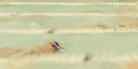 Swimmers swim backstroke at a meet. Panoramic Format.