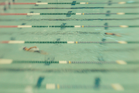 Swimmers swim backstroke at a meet. Abstract motion blur.の写真素材