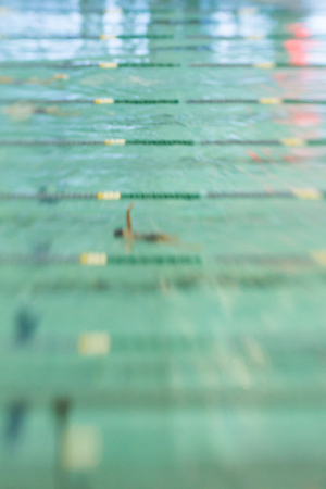 Swimmers swim backstroke at a meet. Abstract motion blur.