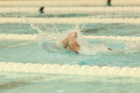 A swimmer swims freestyle at a swim competition.の写真素材