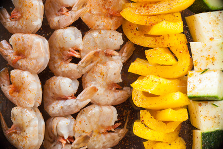 Brightly colored shrimp, zucchini, and orange bell pepper kebabs are raw and ready to be grilled.の写真素材