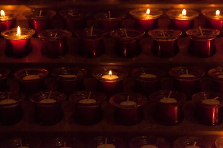 Prayer candles, lit inside a church, give off a warm glow.の写真素材