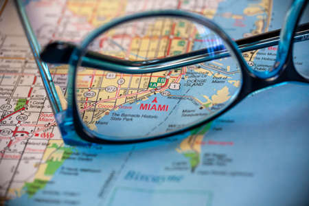 WOODBRIDGE, NEW JERSEY - July 13, 2020: A map of Florida is shown with a focus on Miami, through a pair of eyeglassesのeditorial素材