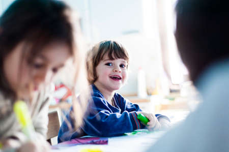 children paint and draw and cut out drawings made by them at the kitchen table in their pajamas on a...