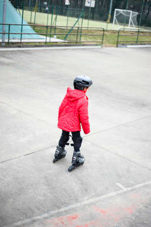 little girl learns to skate with rollerskating at the basketball court on a winter dayの写真素材