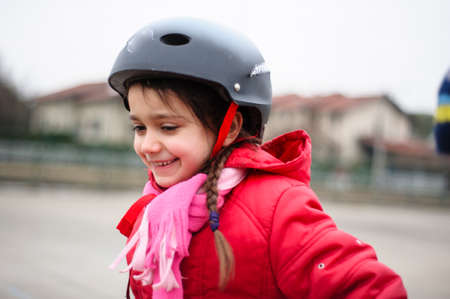little girl learns to skate with rollerblading at the basketball court on a winter day