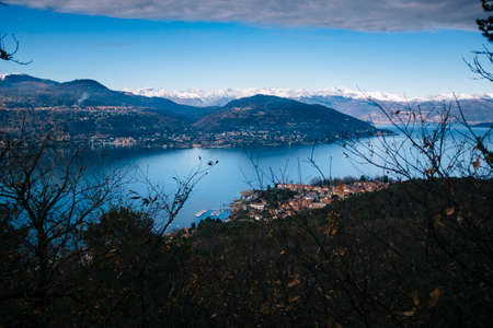 Italy, Piedmont, Lake Maggiore, panorama of Lake Maggiore with snow-covered alps chain, view of the small lakeside village Rancoの写真素材