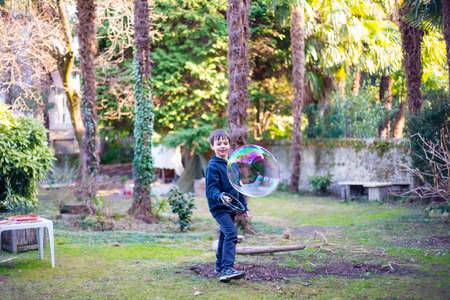 7-year-old child outdoors in the garden in winter makes big soap bubblesの写真素材