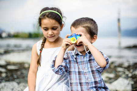 portrait of a brother and sister children with toy camera, in summer outdoorのeditorial素材
