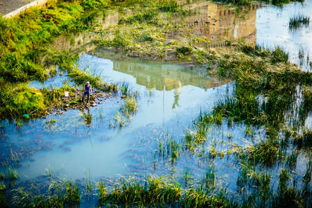 Italy, Rome, Castello Sant'Angelo is reflected in the Tiber, a fisherman fishing among the vegetation of the riverの写真素材